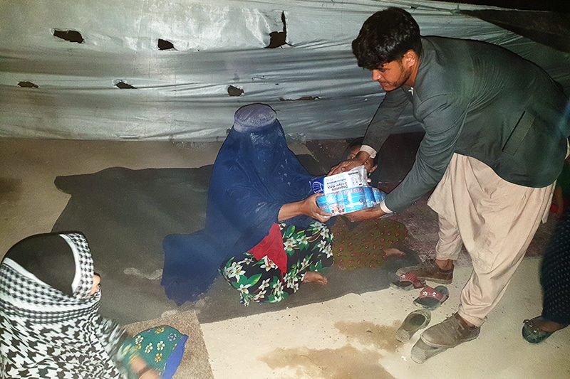 Aid worker handing aid package to woman