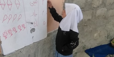 Pakistani girl writing on blackboard
