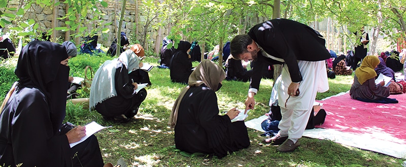 Students sitting outside in the grass in Afghan school