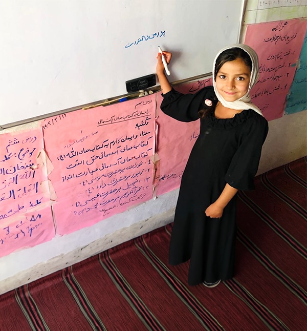 Girl writing on board in classroom