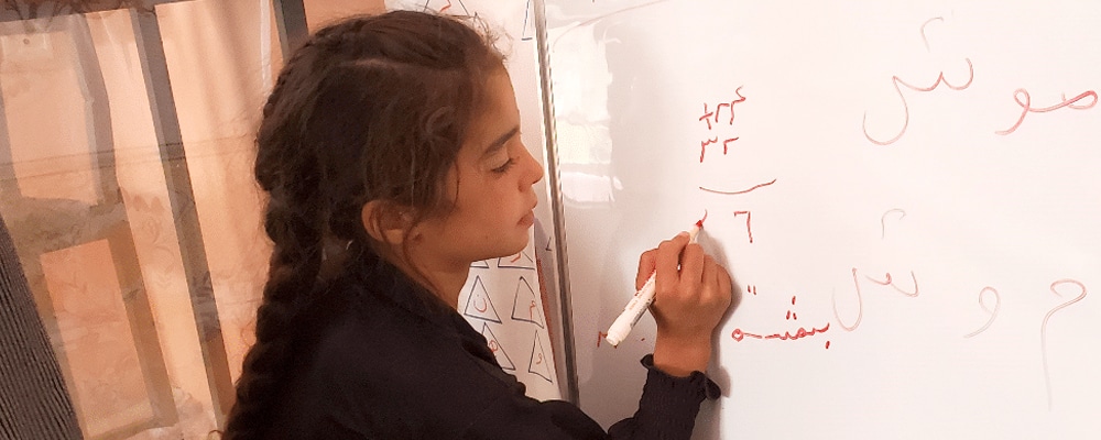 Beheshta writing on white board in class