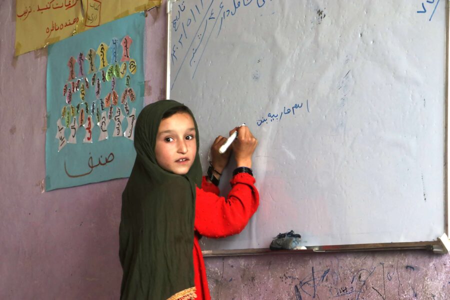 Afghan girl writing on board in class