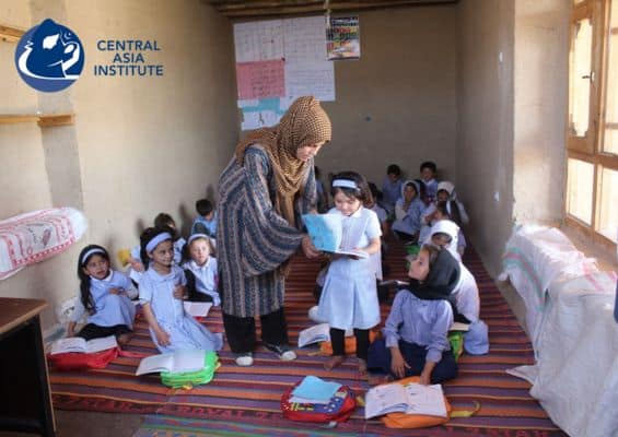 Female Afghan teacher helps a girl student in a classroom