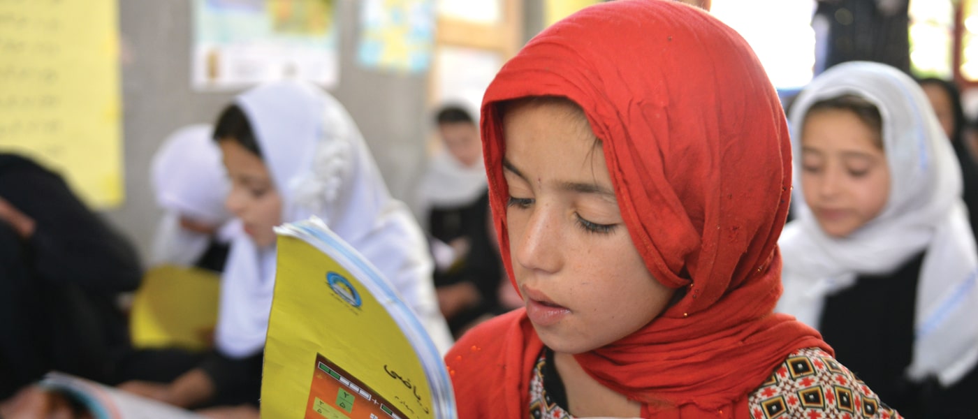Girl with red headscarf reading a book